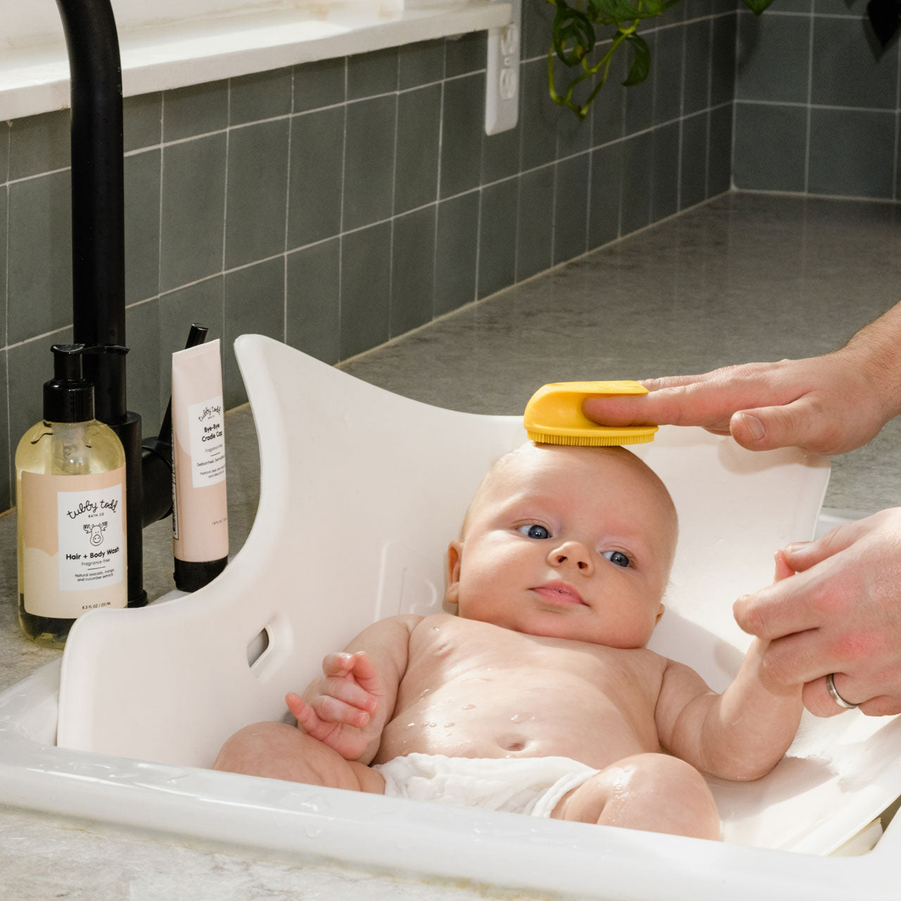 Dad applying Bye-Bye Cradle Cap onto baby's scalp using yellow silicon brush